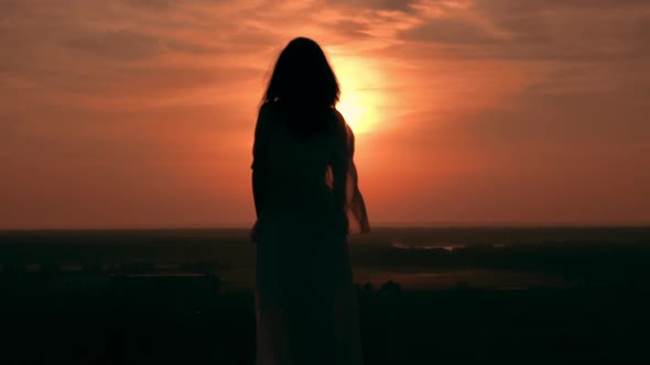 Silhouette Woman with Long Hair Standing on the Hill at Sunrise alt