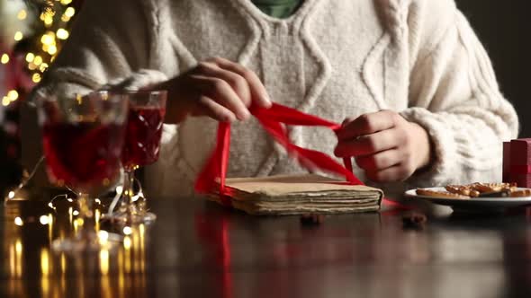 Woman in sweater is wrapping a Christmas gift on a table