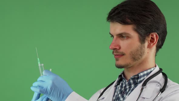 Male Medical Worker Holding a Syringe on Green Background alt