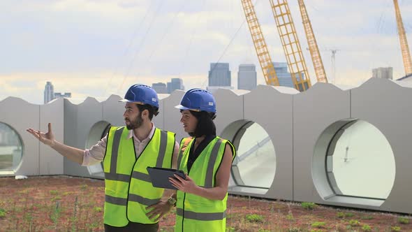 Man and woman discussing with digital tablet at construction site