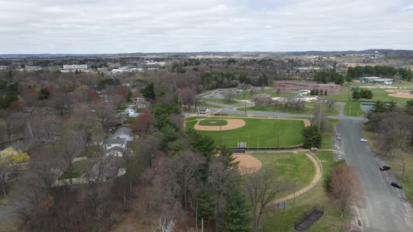 View of sports complex and residential neighborhood. Rural city in distance with mountains.