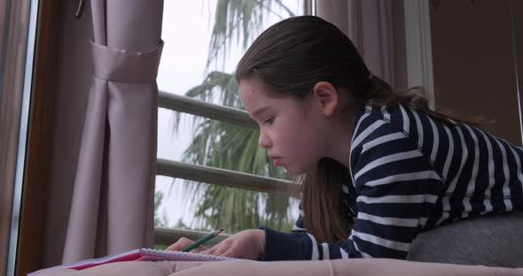 A Little Girl Drawing with Pencils at Home