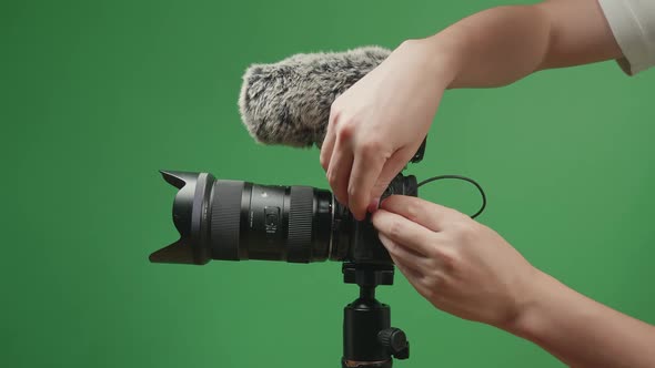 Close Up Hands Male Put Microphone On Digital Camera In Green Screen Studio alt