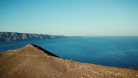 Drone View of Man on Motorbike Extremely Rides Across the Hills with Black Sea on Background 