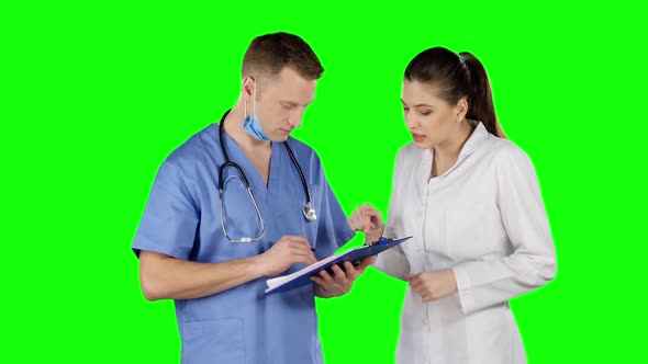 Two Doctors Talking with Clipboard. Green Screen alt