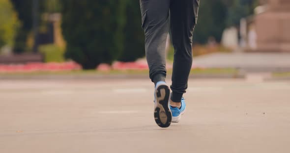 Man in Sneakers Runs Along the Asphalt Road