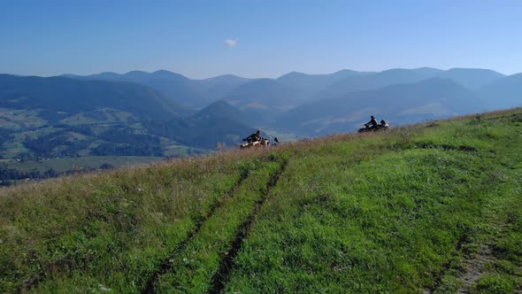 ATV Riders on Grassy Mountain Hill on a Sunny Day in Summer alt
