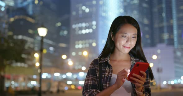 Woman use of mobile phone online in city at night alt