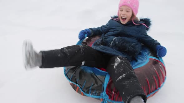 A cheerful happy girl on snow tube