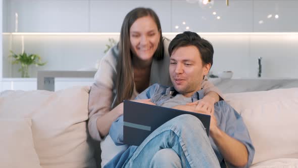 Cheerful Couple Looking at Screen of Laptop alt