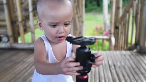 Cute Funny Toddler Curious and Figuring Out How to Use a Tripod Camera alt