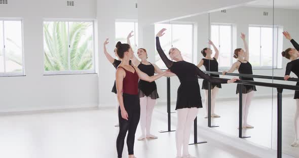 Caucasian ballet female dancers exercising with a barre by a mirror during a ballet class alt