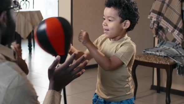 Father training his son to fight with small punching bag