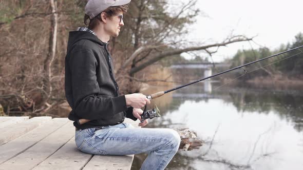 The guy in his free time catches a predatory fish on spinning from the shore. Fishing as a hobby. alt