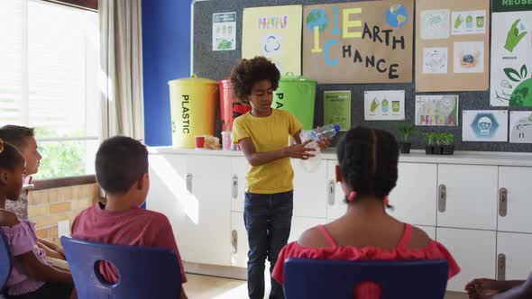 Diverse schoolboy making presentation for his colleagues how to recycle plastic trash alt