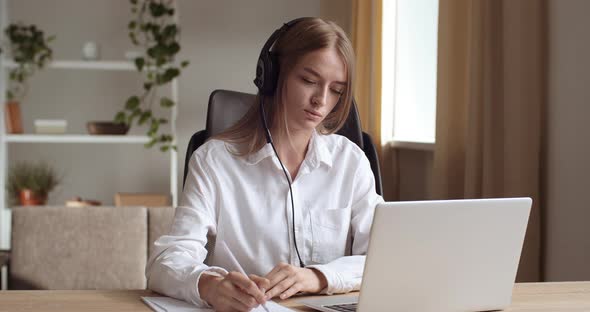 Focused Student Girl Wear Headphones Studying on Laptop Writing Notes, Woman Prepare for Test Exam alt