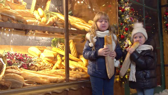 Siblings Eating Bread Near Bakery in Evening