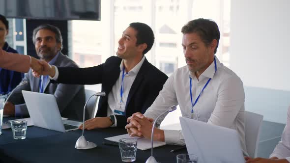 Business delegates shaking hands at a conference alt