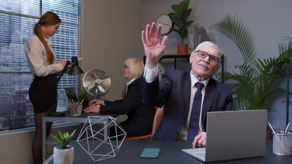 Senior Businessman with Colleagues Team Waves Palm in Hello Gesture Welcomes Someone in Office alt
