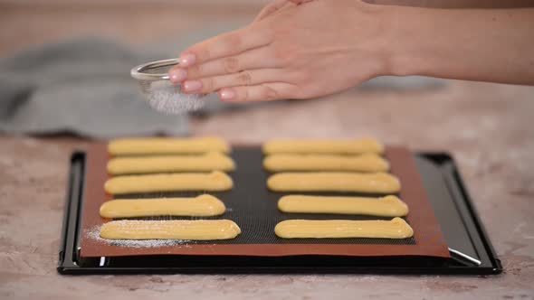 Sprinkle raw dough for eclairs on a baking sheet with powdered sugar.