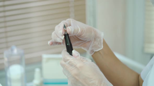 Beautician is Showing a Brush with a Needle at the end in Her Hands for Permanent Makeup alt