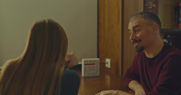 Young Man Sits at a Table with a Woman and Communicates Nicely with Her a Meeting in the Library alt
