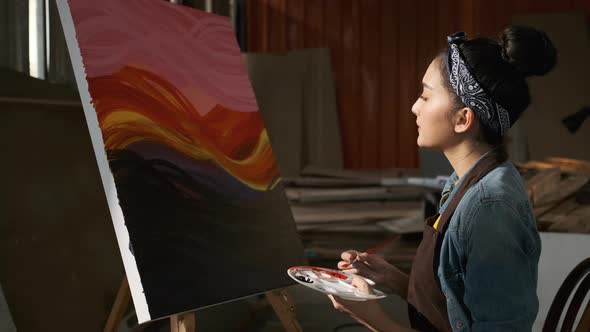 Asian Female Artist Draws create art piece with palette and brush painting at studio.