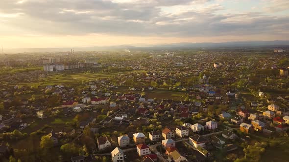 Aerial view of rural area in town with residential houses at sunset summer evening. alt