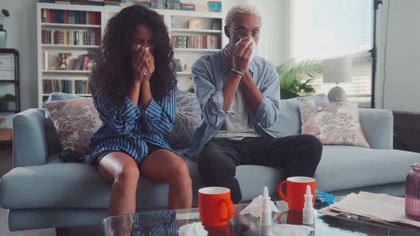 Mixed Race Young Couple Sneezing Noses Suffering From Headache in Living Room alt