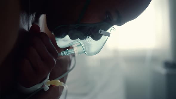 Male Patient in Oxygen Mask Breathe Crossing Arms in Intensive Care Unit Closeup alt