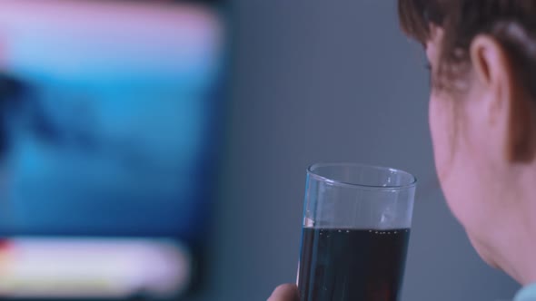 Back View of a Brunette Woman Middleaged Watching Tv and Drinking Soda Cinematic Shot
