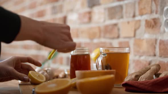 Hands of unrecognizable woman cutting lemon for winter tea. Shot with RED helium camera in 8K. alt