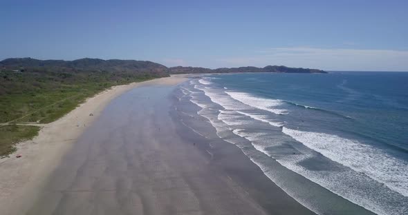 Aerial drone view of the beach, rocks and tide pools in Guiones, Nosara, Costa Rica alt
