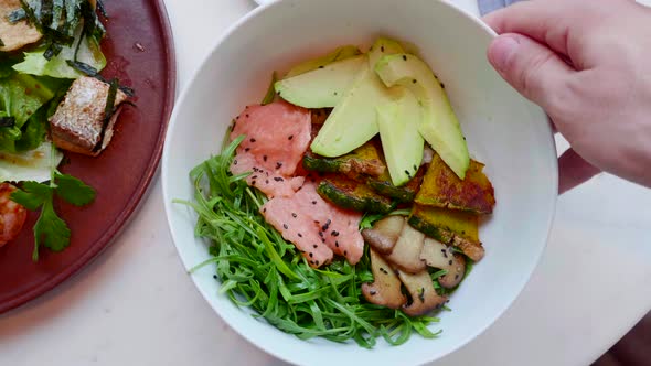 Salmon Salad with Avocado Zucchini Top View Hand Rotating alt