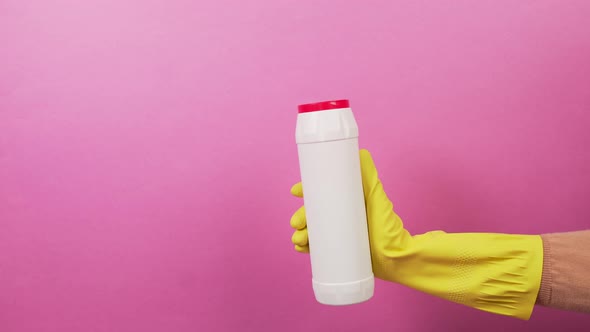 A Hand in a Glove with a White Bottle with a Red Lid with Household Chemicals