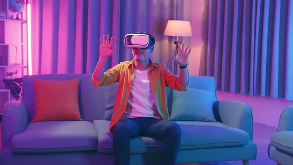 Young Asian Man Wearing Vr Headset At Living Room, Cyan And Magenta Colors alt