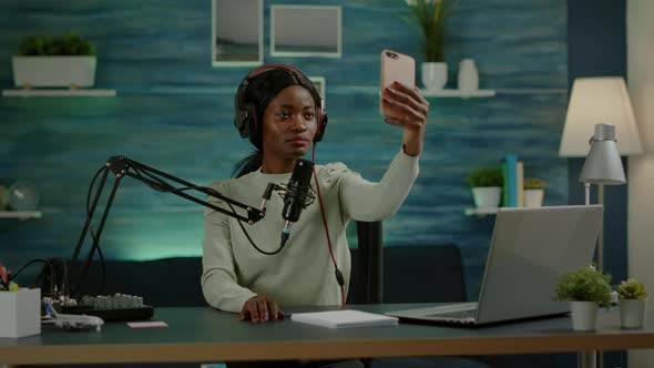 African Woman Using Smartphone Taking Selfie During Podcast alt