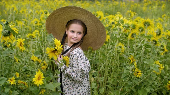 Beautiful Smiling Teen Girl in Wicker Hat Posing in Sunflower Field alt