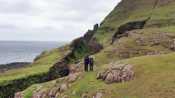Aerial Back View of Unregnisable People Looking the Huge Cliffs in Faroe Islands Green Rocky alt