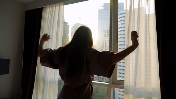 Silhouette of Woman Looking at Skyscrapers Outside Window alt