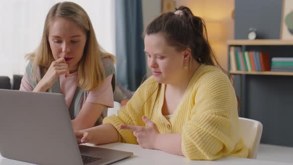 Girl with Down Syndrome Using Laptop with Teacher at Home Lesson alt