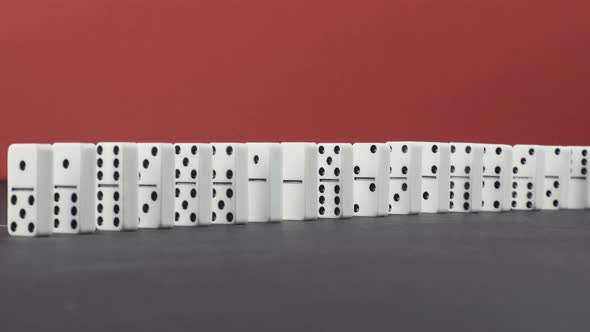 Domino Effect - a Series of Dominoes Falling Down the Chain on Red Background alt