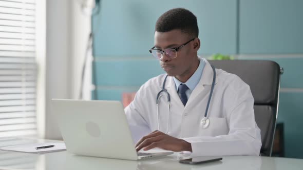 Young African Doctor Smiling at Camera While Using Laptop in Office alt