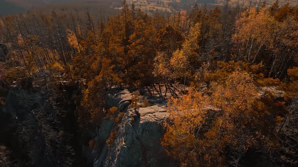 Aerial Drone Circle Flight Around Couple Hikers Sitting on Top of Cliff alt