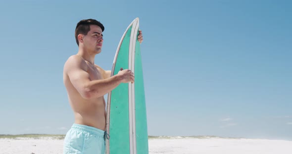 Man holding a surfboard on the beach alt