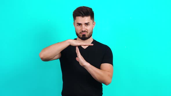 Young Caucasian Guy in a Black T-shirt Looking at the Camera, Showing the Stop Gesture with His Arms alt