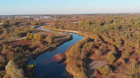 Drone flight over a winding river and autumn red forest alt