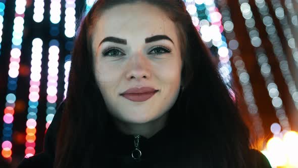 Young Cheerful Woman Portrait Smile and Looking at Camera, Bokeh of Christmas Garland Lights alt