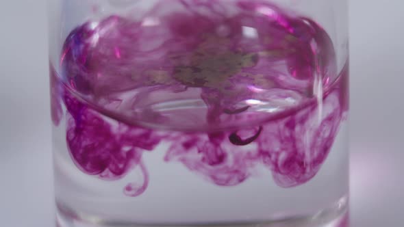 Closeup of Mixing Magenta Colored Substance with Transparent Liquid in a Flask