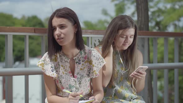 Two Attractive Female Students Sitting Outdoors Together alt